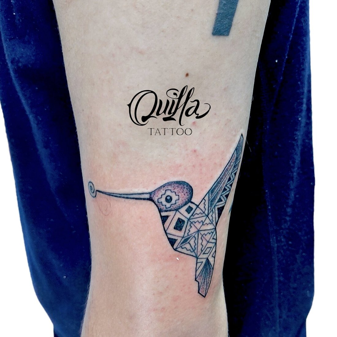Fine line hummingbird tattoo with geometric patterns on arm by Quilla Tattoo
